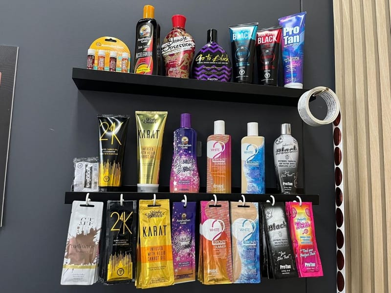 Tanning lotion bottles and hanging sachets on black salon shelves